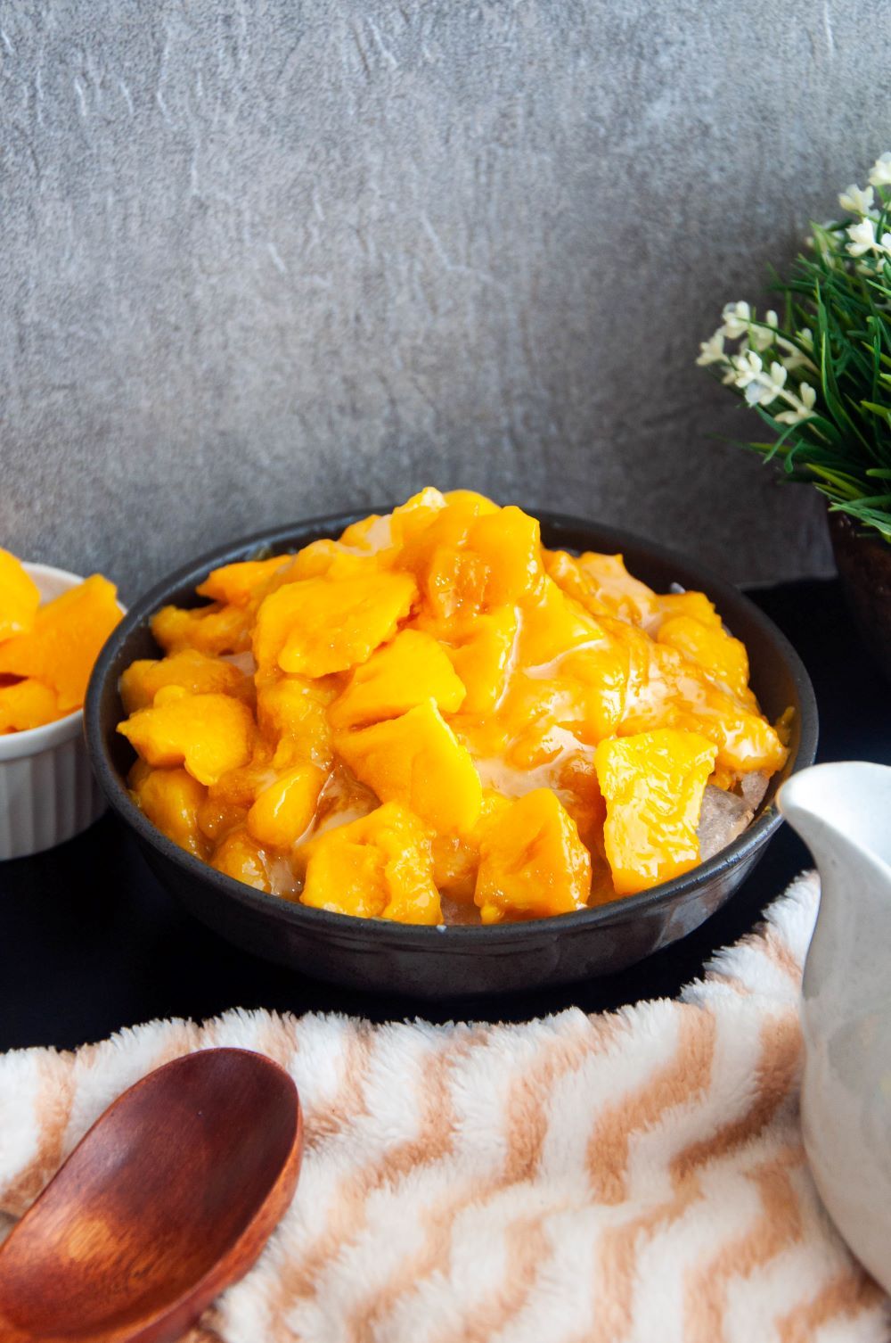Topping the crushed ice with the mango compote and the cubed mangoes