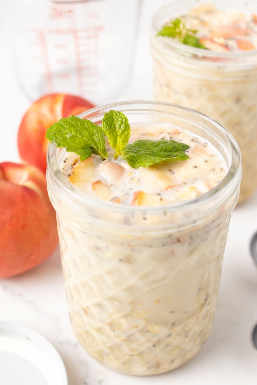 Peach Overnight Oats with fresh peaches in the background