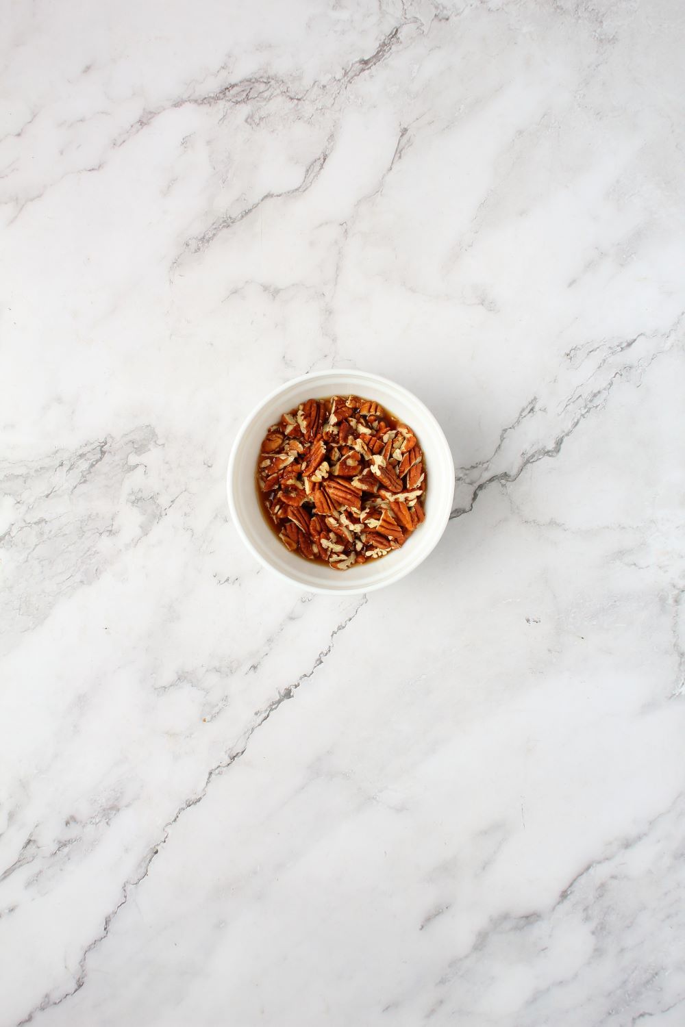 Combining maple syrup and chopped pecans in a bowl